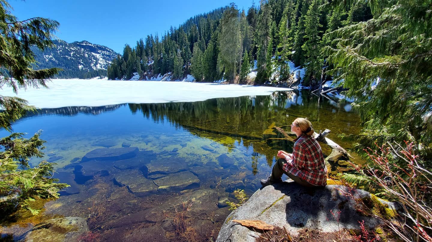 Person sitting by glacial lake